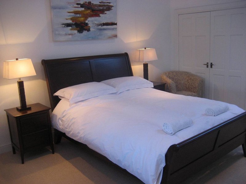 Bedroom with black bed frame, white bedding, two bedside lamps and wardrobe