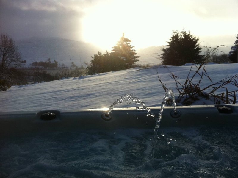 Frozen pond with iced-over surface, bare trees and snow-covered landscape at sunset