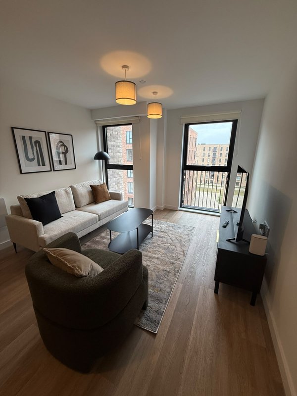 Modern living room with cream sofa, black armchair, pendant lights and city views