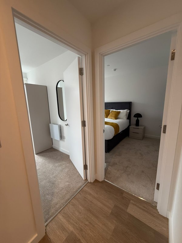Hallway with wood flooring leading to bedroom and bathroom doorways