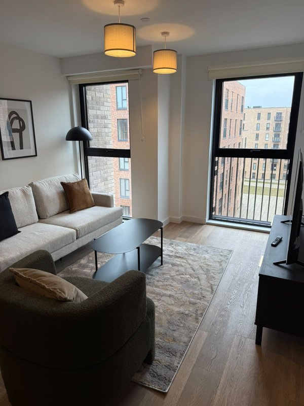Modern living room with cream sofa, brown armchair, pendant lights and city views