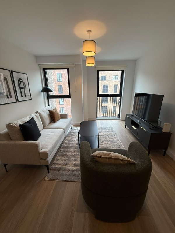 Modern living room with cream sofa, dark armchair, wooden floors and pendant lighting