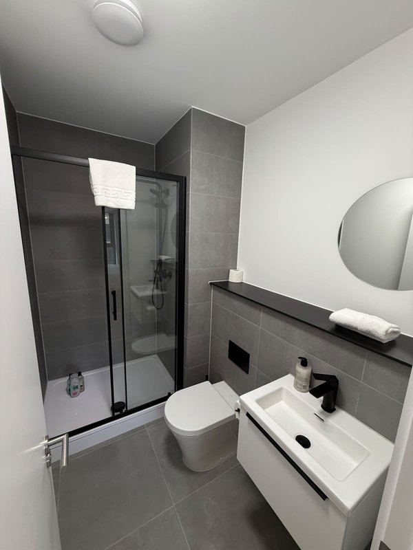 Modern bathroom with shower cubicle, toilet, sink and round mirror