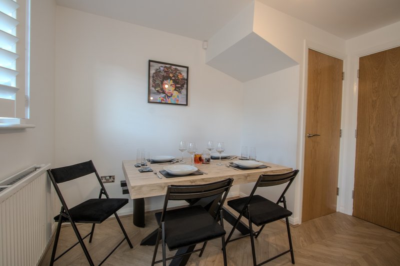 Dining area with wooden table, black chairs, place settings and wall art