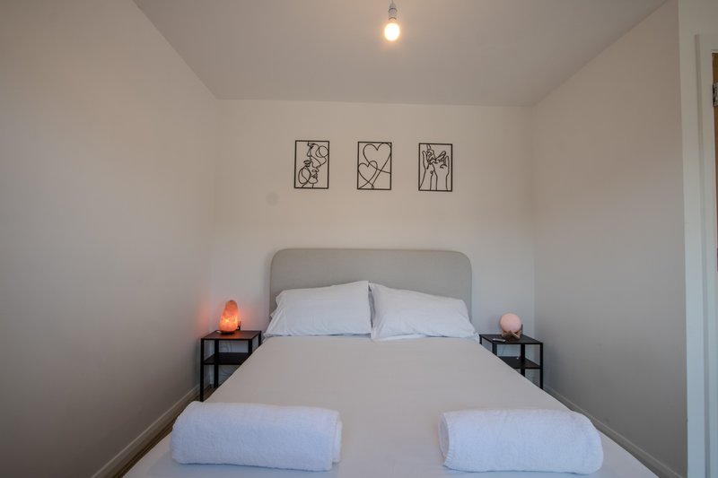 Minimalist bedroom with double bed, grey headboard, white bedding and wall art