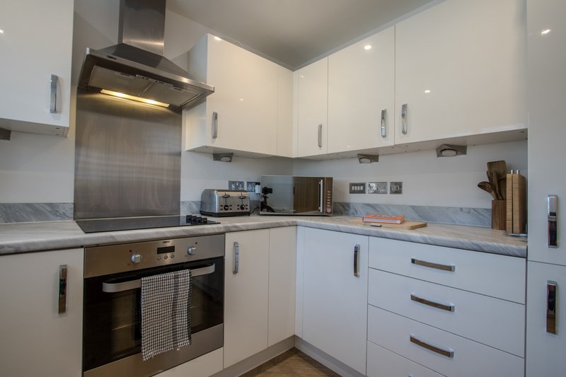 Modern white kitchen with stainless steel appliances, extractor hood and integrated oven