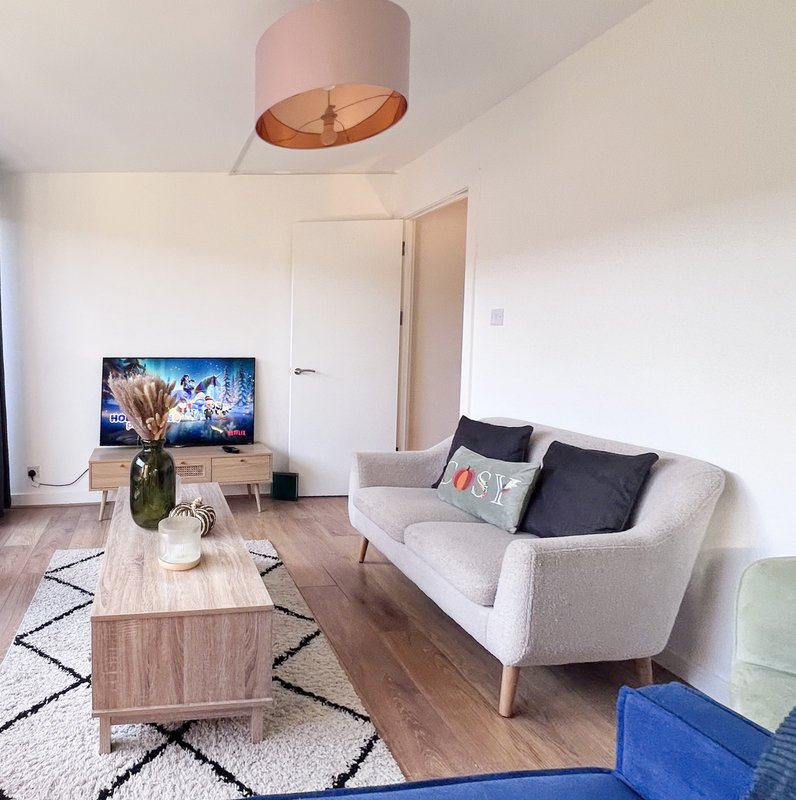 Modern living room with grey sofa, wooden coffee table, TV, and pendant light fixture