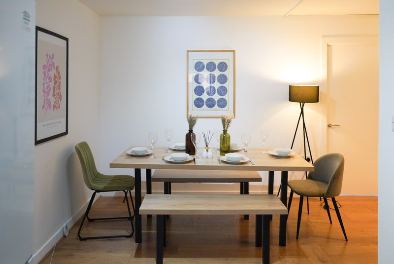 Modern dining room with wooden table, bench seating, upholstered chairs, wall art, and tripod lamp