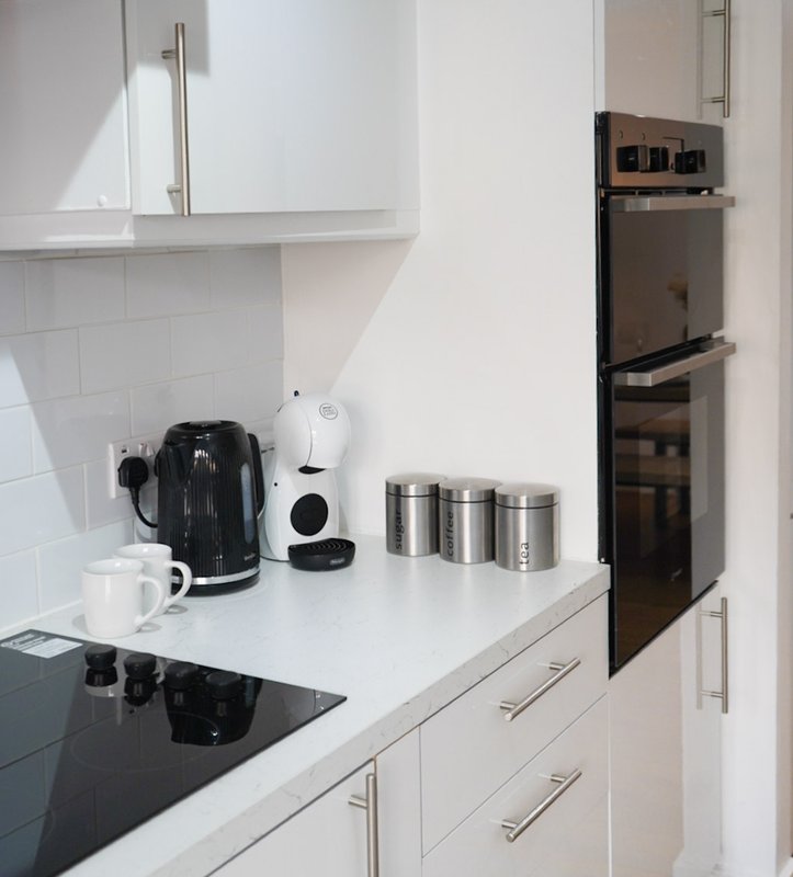 Modern kitchen with white cabinets, black cooktop, stainless steel appliances and countertop