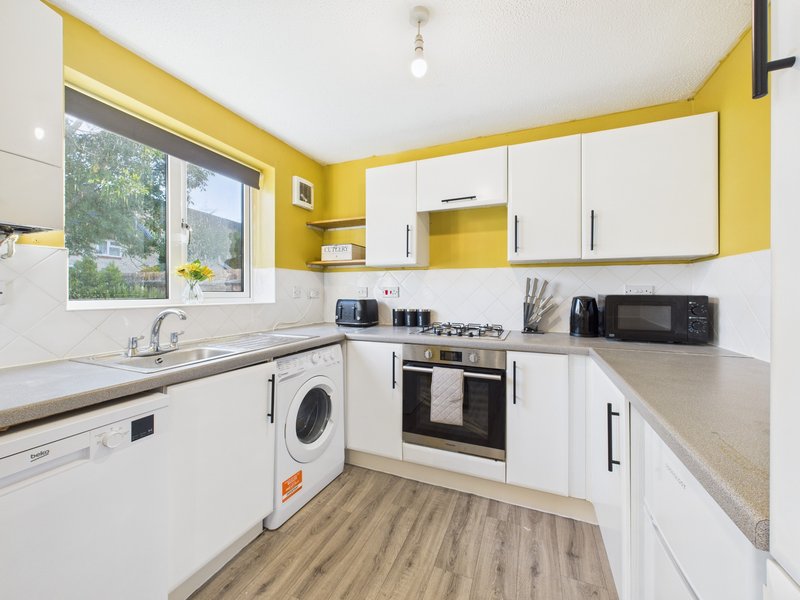 Modern kitchen with yellow walls, white cabinetry, stainless steel appliances and wooden flooring