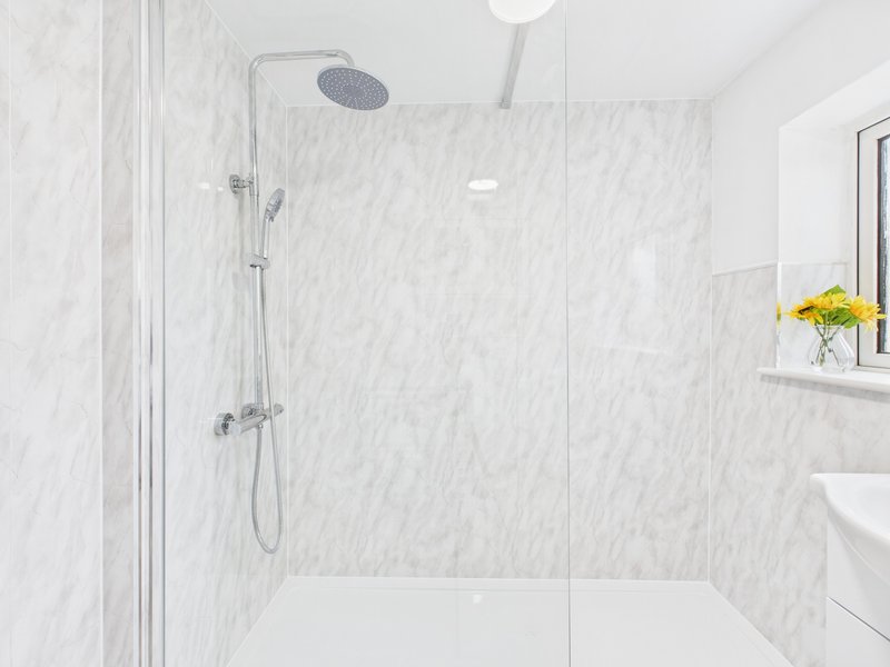 Modern bathroom with marble-tiled walk-in shower, rainfall showerhead, and white sink