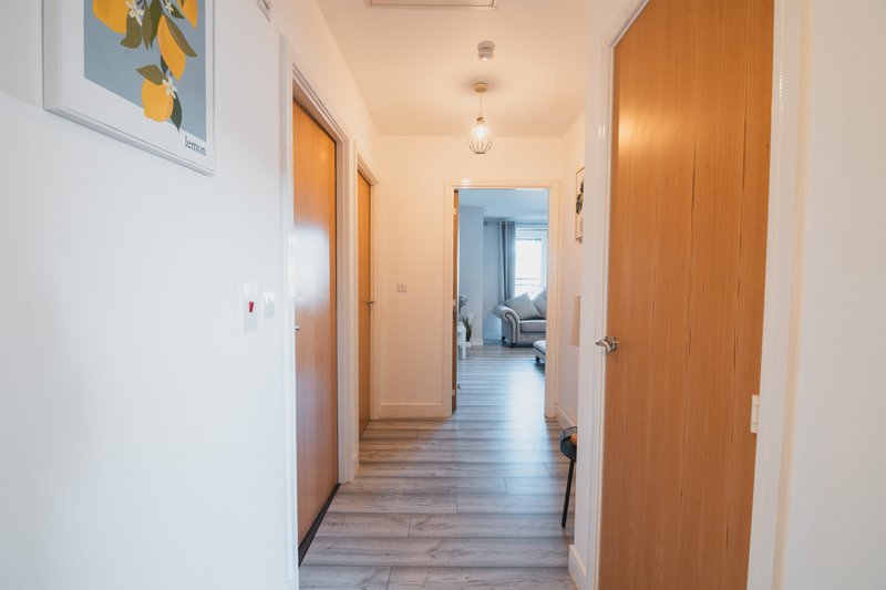 Bright hallway with wooden doors, light wood flooring and framed artwork on wall