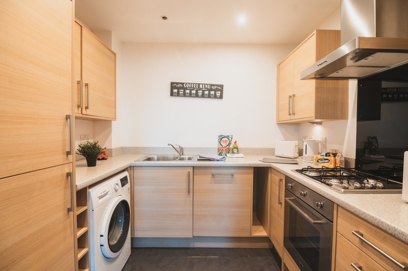 Modern kitchen with wooden cabinets, stainless steel appliances, washing machine and countertop