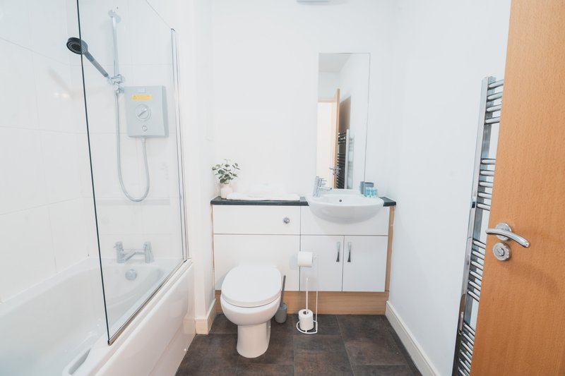 Modern bathroom with white toilet, vanity sink, shower enclosure and heated towel rail