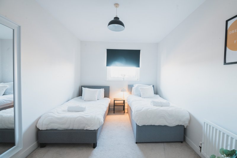 Twin bedroom with two single beds, pendant light, window with blind and framed artwork