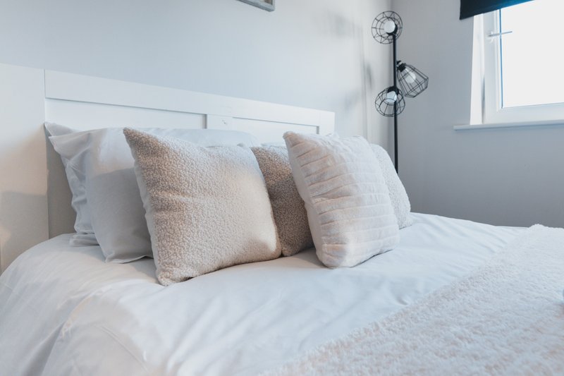 Modern bedroom with white bed, decorative pillows, white headboard and window