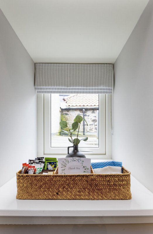 Windowsill with woven basket containing plant, books and decorative items