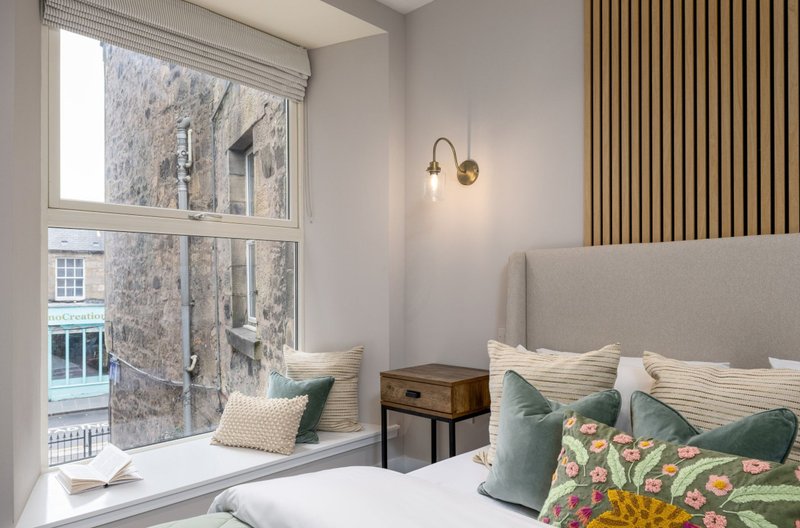 Modern bedroom with double bed, window seat, pendant lighting and striped curtains
