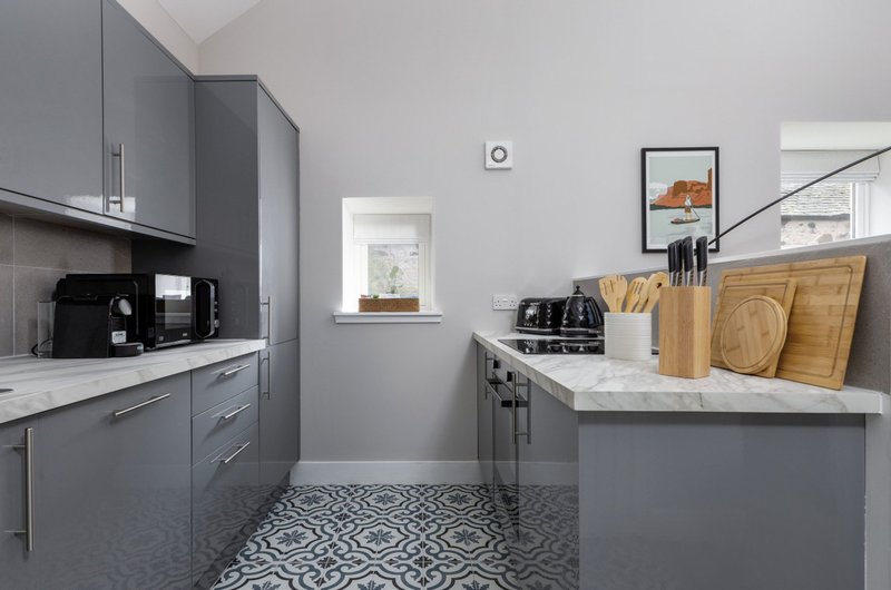 Modern kitchen with gray cabinetry, marble countertops, stainless steel appliances and patterned flooring