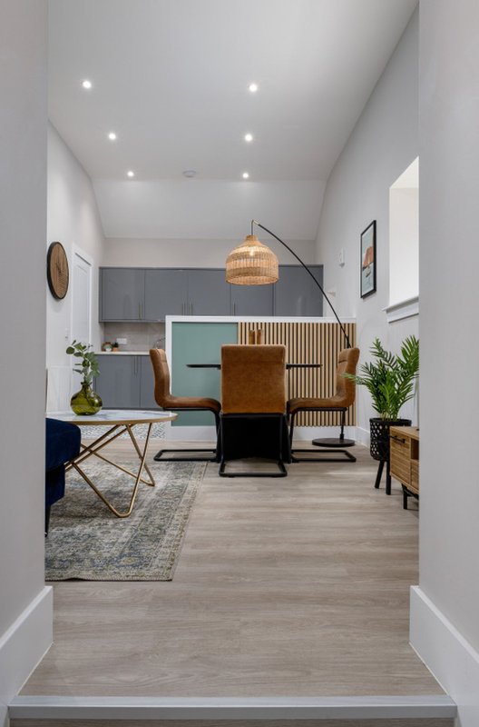 Modern open-plan living space with kitchen, dining area, pendant lighting and contemporary furnishings