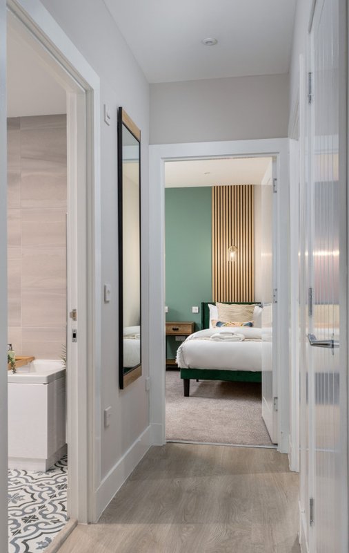 Hallway view showing bathroom entrance on left and bedroom with green accent wall on right