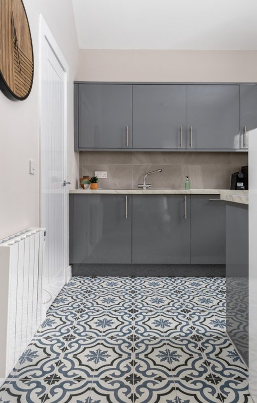 Modern kitchen with grey cabinetry, patterned tile floor, and stainless steel sink