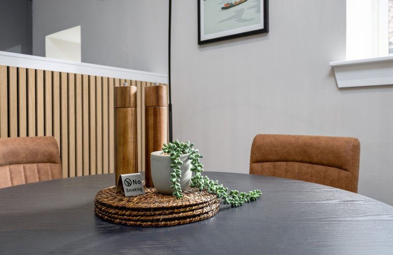 Modern dining area with dark table, brown upholstered chairs, wooden headboard and potted plant