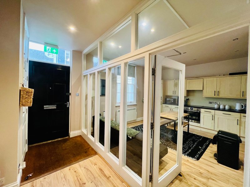 Modern kitchen with cream cabinetry, wooden flooring, and glass sliding doors from hallway