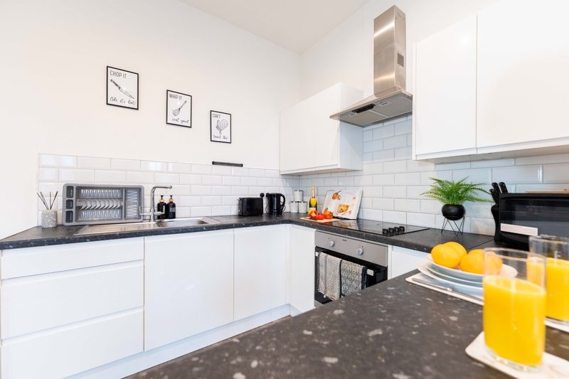 Modern white kitchen with dark worktops, stainless steel appliances and white subway tiles