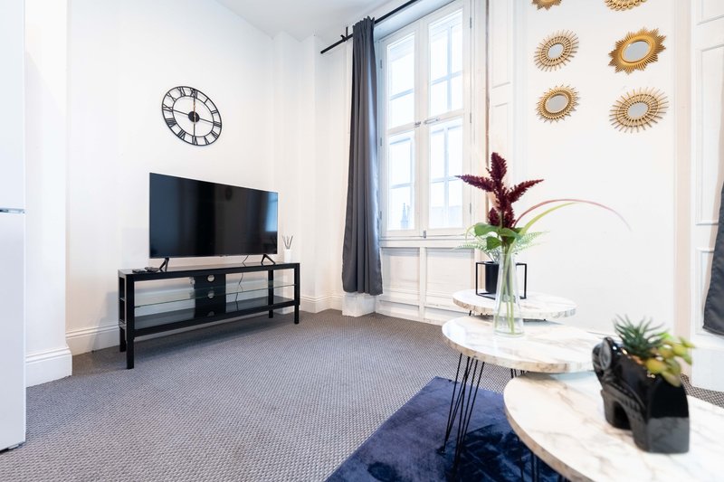 Modern living room with TV, black media console, decorative clock and wall art