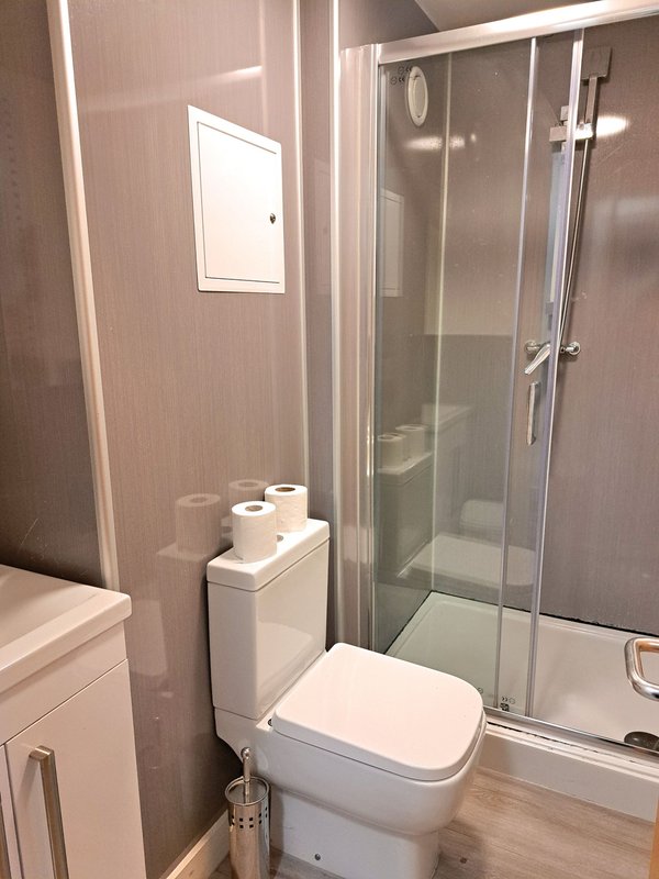 Modern bathroom with toilet, glass shower enclosure, and small window
