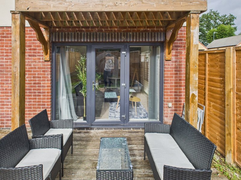 Brick extension with pergola, patio seating and glass sliding doors to interior