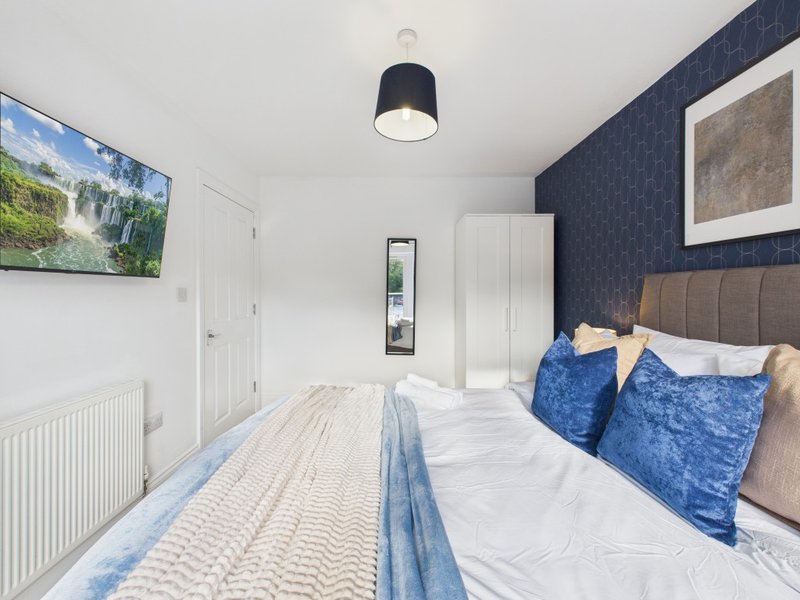 Modern bedroom with double bed, blue velvet pillows, dark feature wall and ceiling lamp