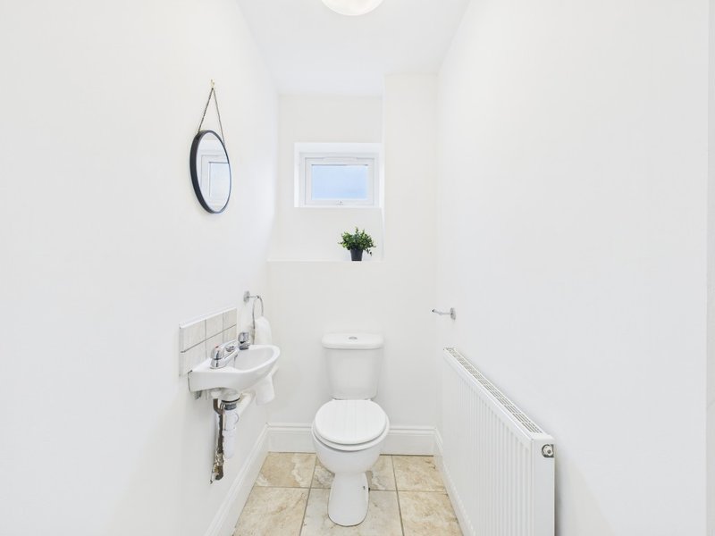 Small bathroom with white toilet, wall-mounted sink, mirror and window
