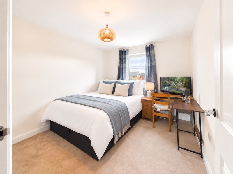 Modern bedroom with double bed, wooden desk, pendant light and grey curtains