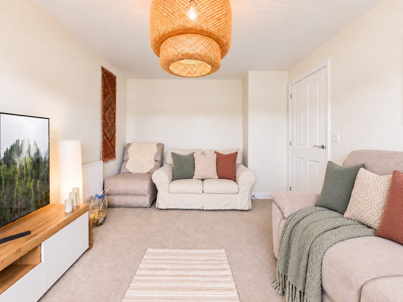 Bright living room with neutral seating, woven ceiling light, wooden console and framed wall art