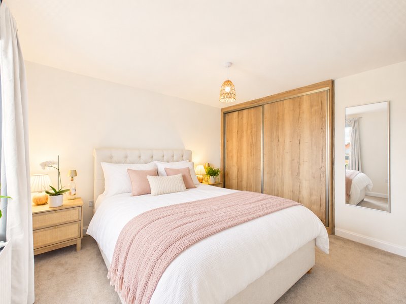 Bright bedroom with double bed, wooden wardrobe, bedside table and mirror
