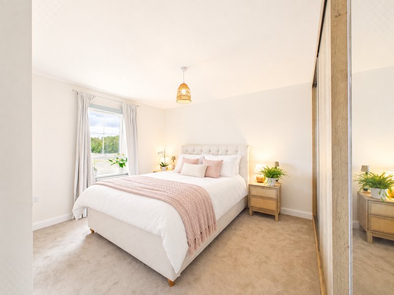 Bright bedroom with double bed, pink bedding, wooden nightstands, pendant light and window