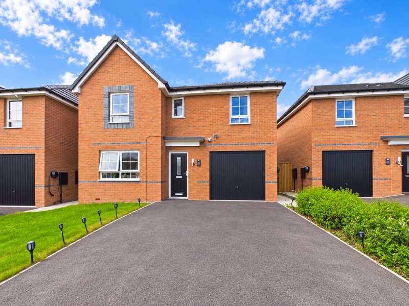 Modern brick detached house with driveway, black garage door and front garden