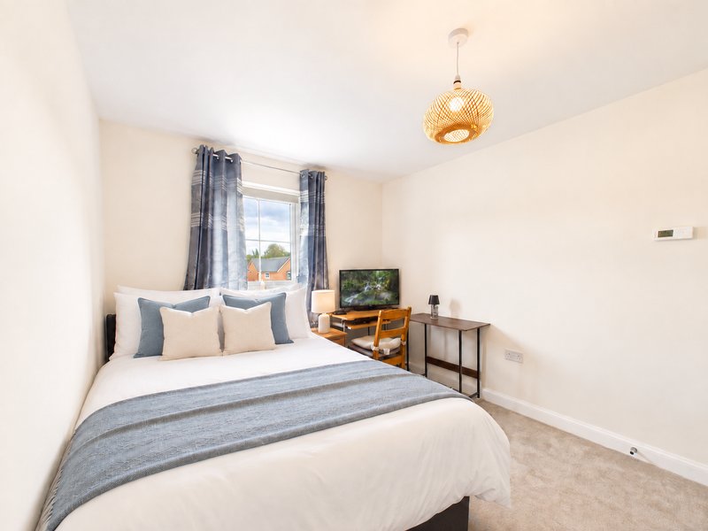 Modern bedroom with double bed, blue striped bedding, wooden furniture and gold pendant light