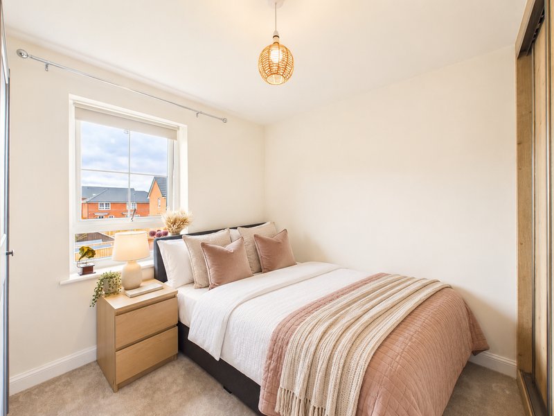 Bright bedroom with double bed, wooden bedside table, pendant light, and window view of buildings