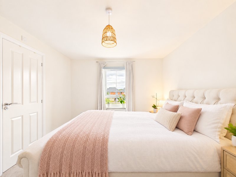 Bright bedroom with double bed, pink bedding, pendant light and window with garden view