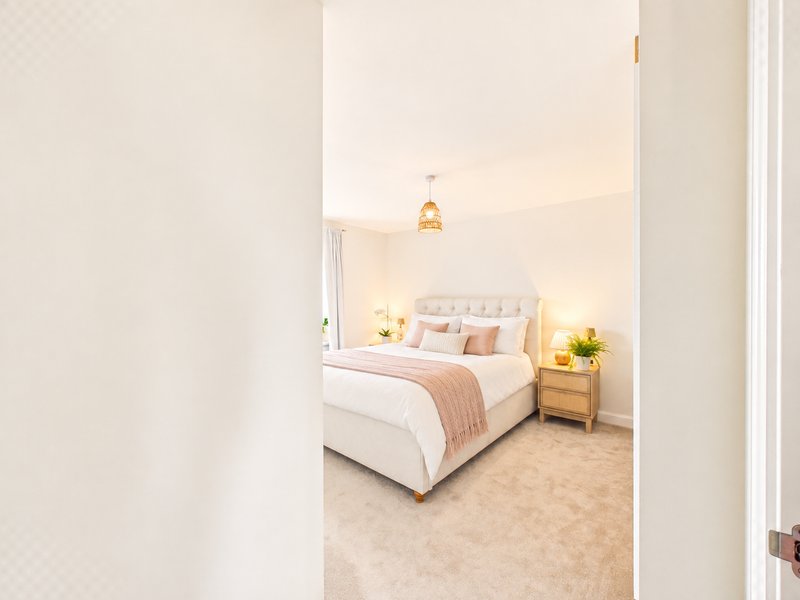 Bright bedroom with double bed, pink bedding, wooden nightstand and pendant light