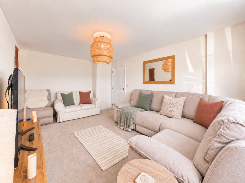 Spacious living room with cream sofas, striped rug, woven pendant light and framed mirror