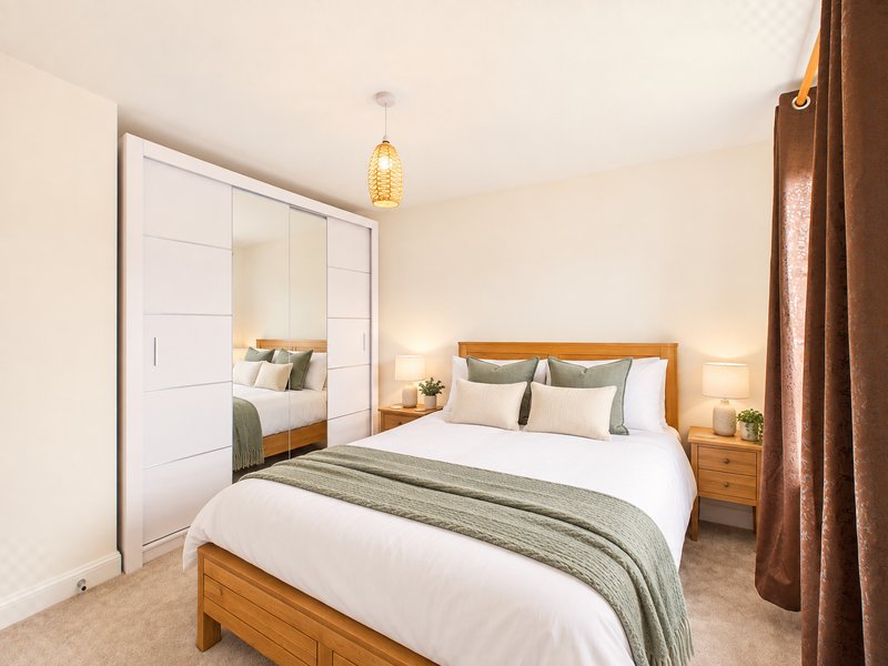 Modern bedroom with wooden bed, white bedding, mirrored wardrobe and pendant light