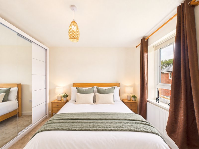 Modern bedroom with double bed, wooden headboard, pendant light and mirrored wardrobe