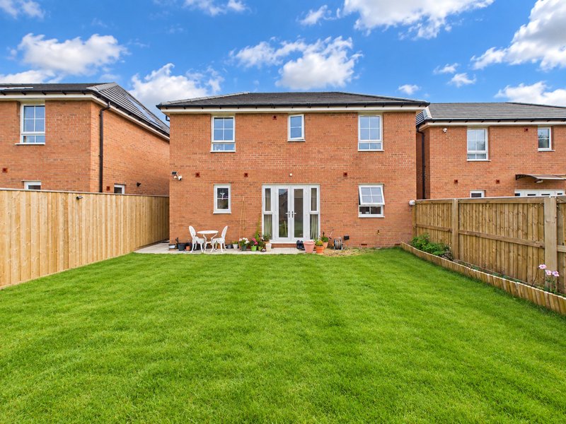 Brick detached house with garden, patio furniture, wooden fencing and lawn