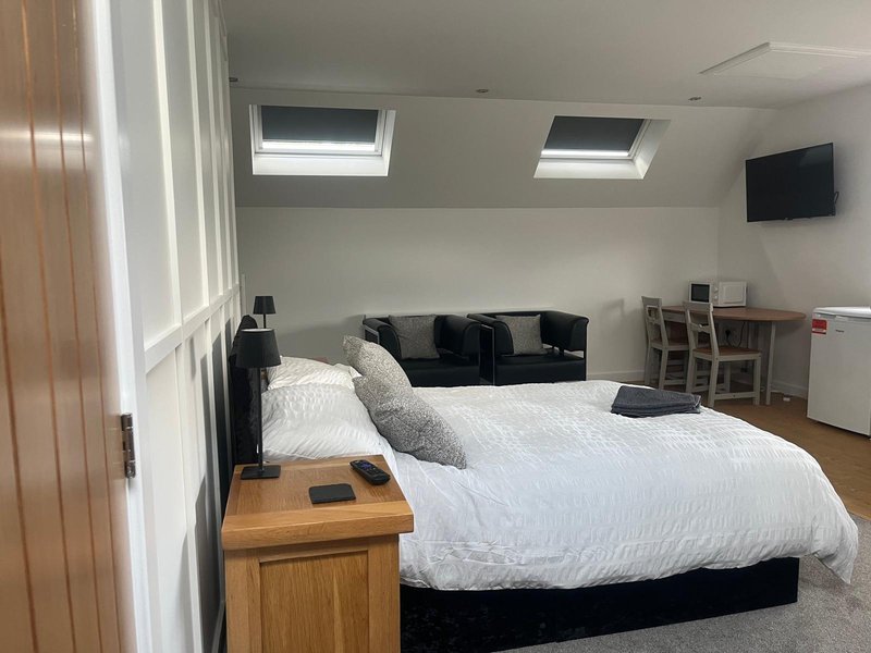 Bright bedroom with two single beds, wooden furniture, skylights and wall-mounted TV