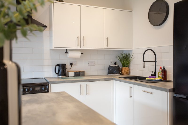 Modern kitchen with white cabinetry, subway tile backsplash, stainless steel appliances and wooden countertop