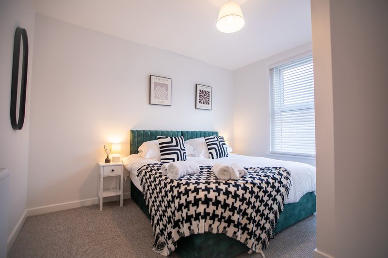 Modern bedroom with double bed, patterned bedding, bedside lamps and framed wall art